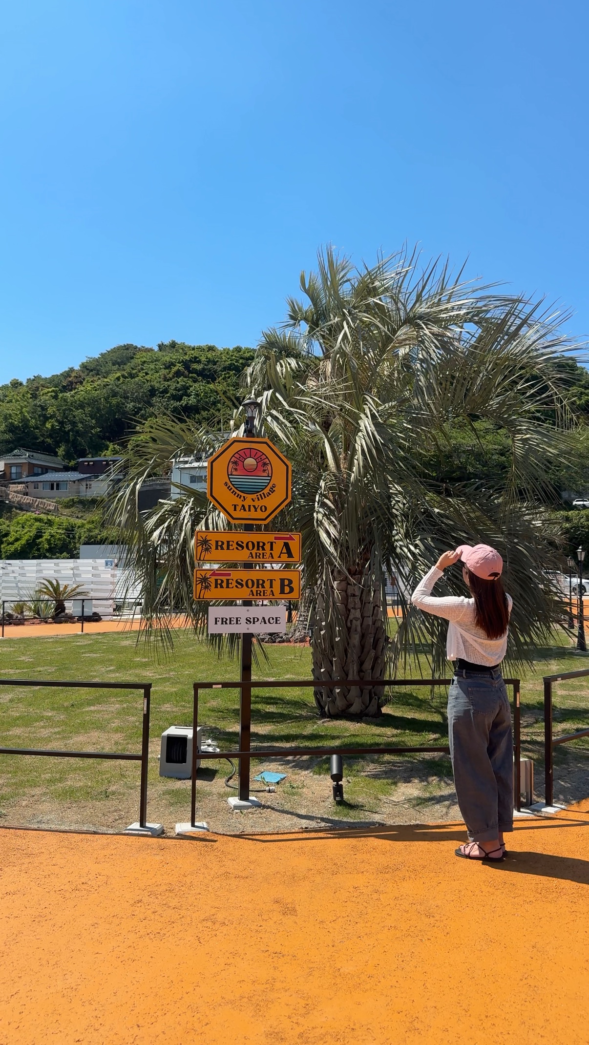 ヤシの木のそばに立つTAIYO sunny villageの案内看板