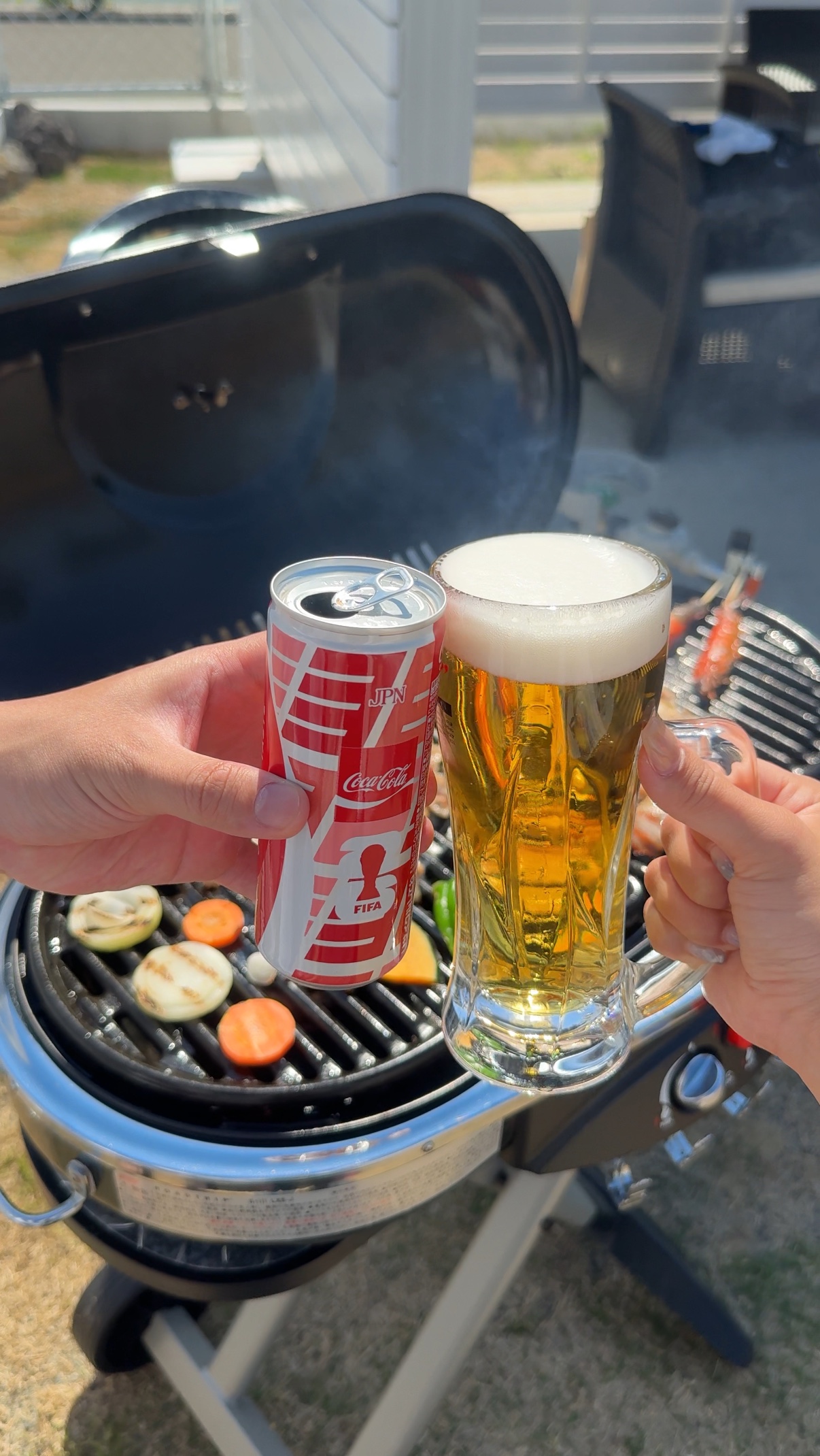 BBQグリルの前でドリンクを持って乾杯する様子